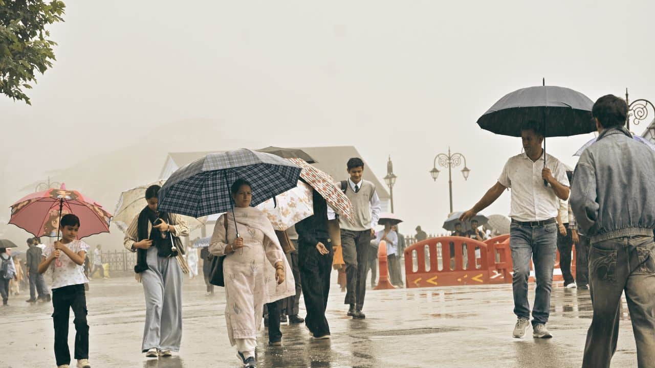 रिज मैदान पर बारिश के दौरान गुजरते लोग।