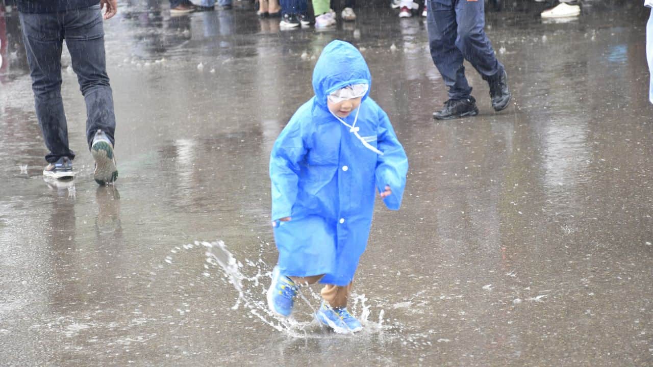 शिमला के रिज मैदान पर रेन कोट पहने बच्चा।