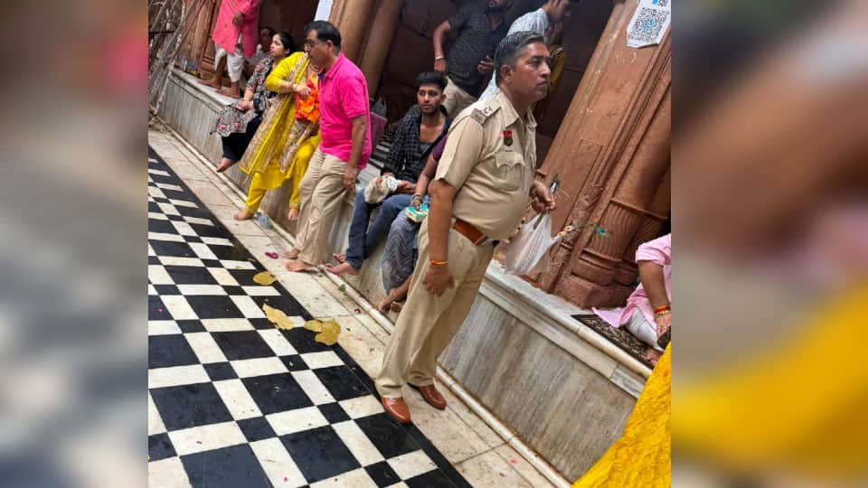 मंदिर परिसर में जूते पहनकर खड़ा पुलिसकर्मी।
