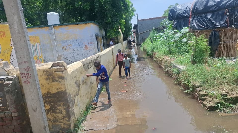 गांव नगला विशी में स्कूल के रास्ते में जलभराव से निकलते बच्चे