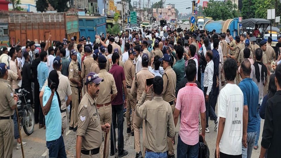 हाईवे पर बैठे लोगों को हटाते पुलिस कर्मी।