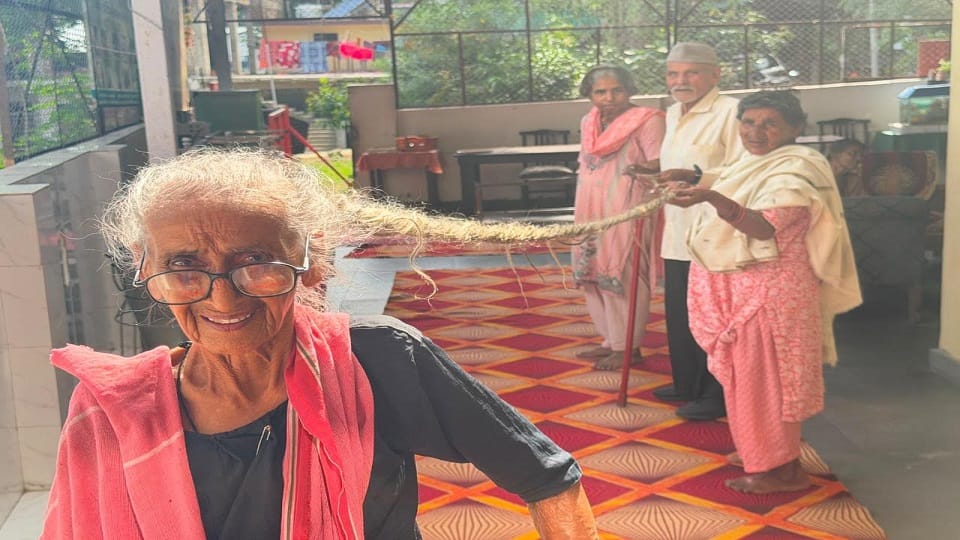 संतोष नाथ के 14.10 फीट लंबे बाल दिखाते वृद्धाश्रम के व्यवस्थापक प्रकाश डिमरी।