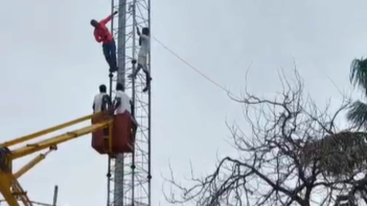 मोबाइल टावर पर चढ़े युवक को उतारते लोग