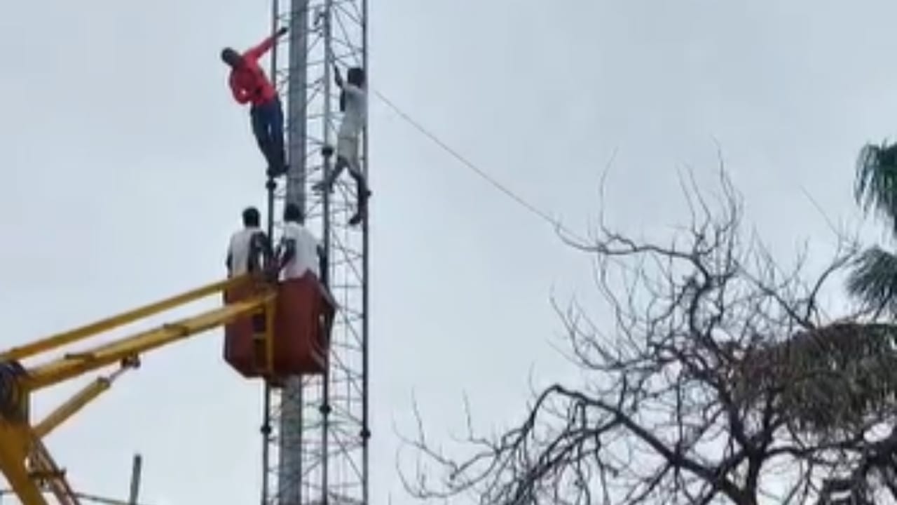 मोबाइल टावर पर चढ़े युवक को उतारते लोग