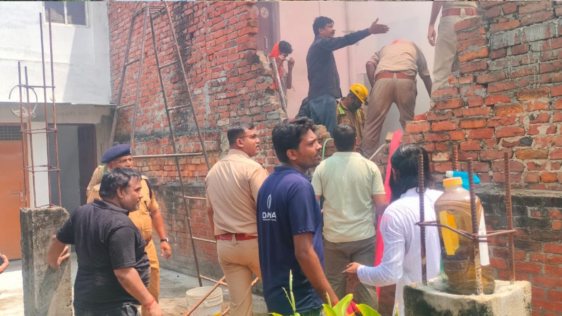 दीवाल तोड़कर अंदर जाते सुरक्षाकर्मी और अन्य लोग
