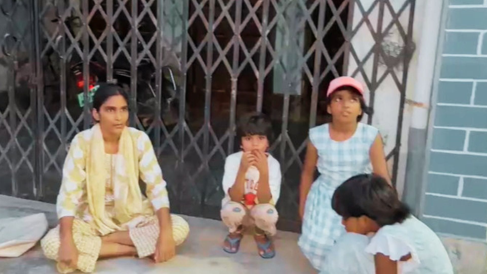 आरोपी के घर के बाद बच्चों के साथ बैठी महिला।