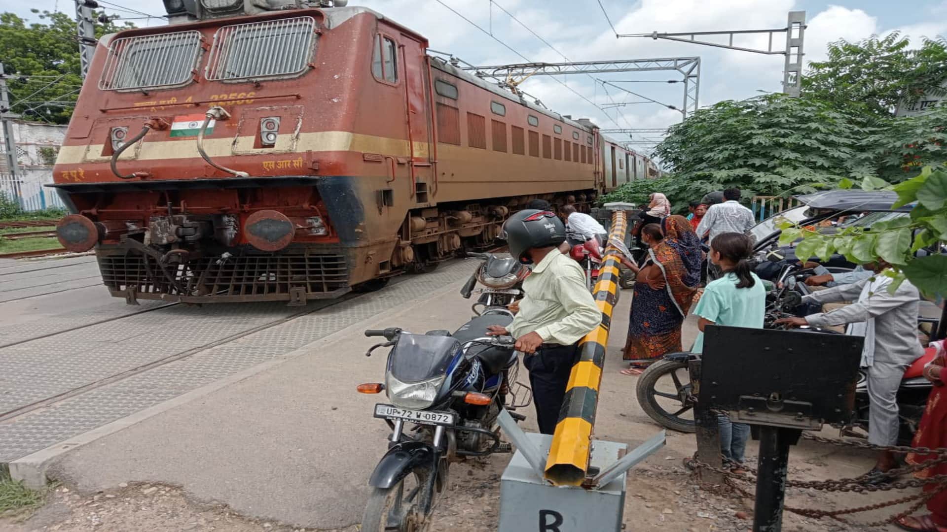प्रतापगढ़ में ट्रेन गुजरने के दौरान बैरियर के अंदर बाइक लेकर खड़े लोग।
