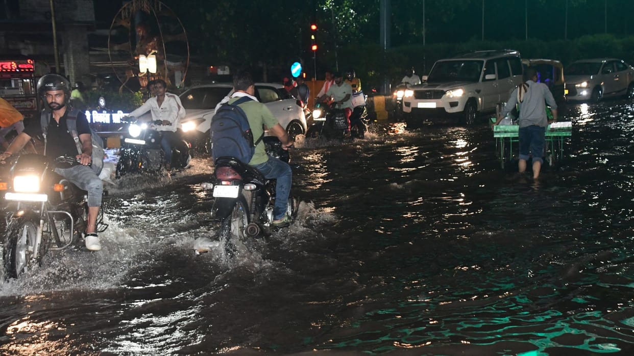 Rain from city to village in varanasi Knee-deep water people forced to drag two wheelers difficult