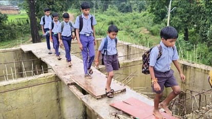 a swift river below, school bags above; children trudge to school via the stairs of an unfinished bridge