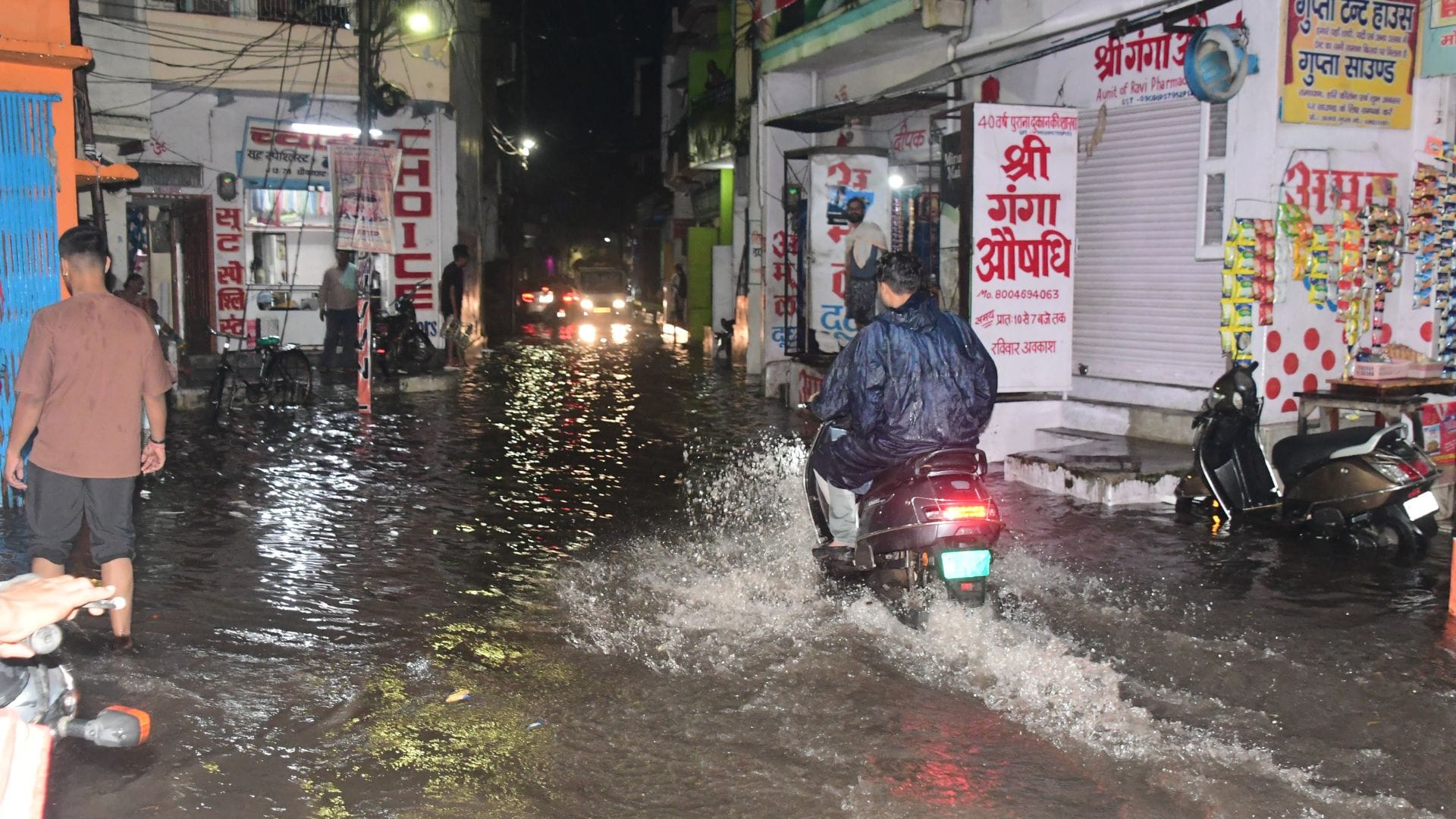 Rain from city to village in varanasi Knee-deep water people forced to drag two wheelers difficult