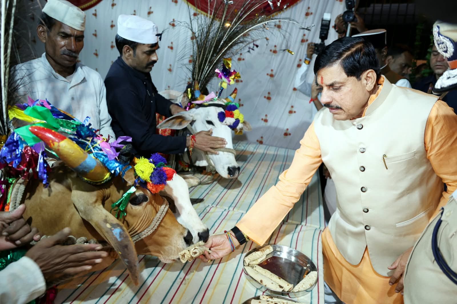 सीएम यादव गौमाता को रोटी खिलाते हुए