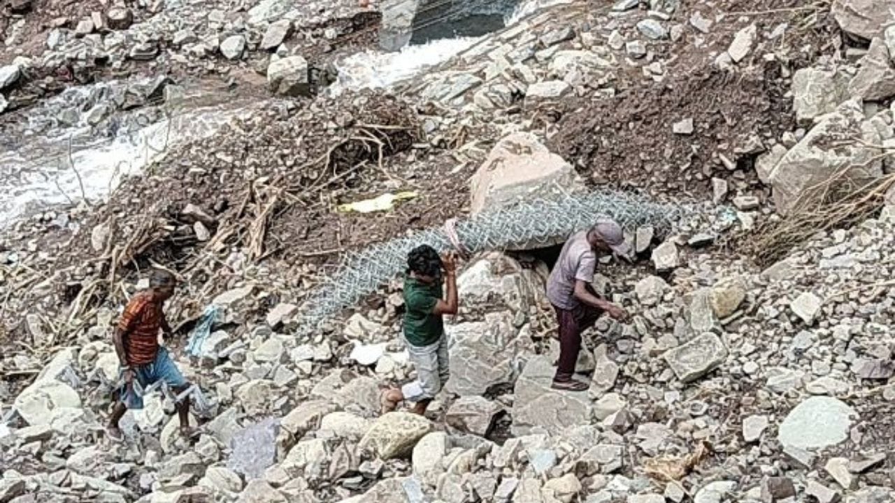ब्रिज नंबर 57 के पास बारिश के कारण नाले में बही क्रेट वायर ऊपर लाते कर्मचारी।