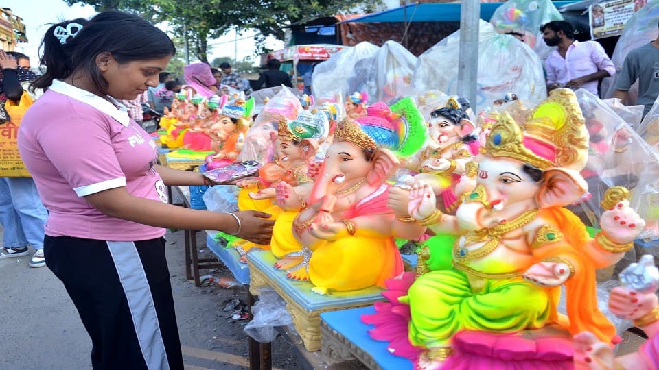 तहसील कोल के पास गणेश महोत्सव को लेकर गणेश जी की प्रतिमा पसंद करती युवती
