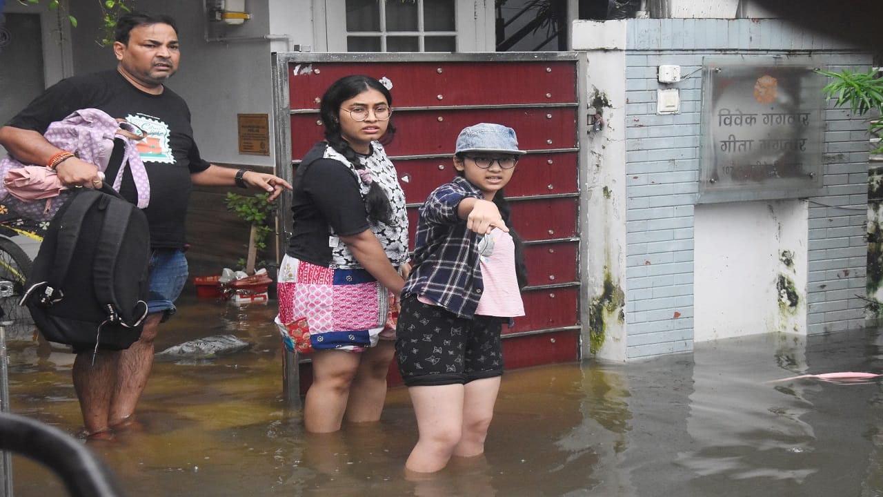रेजीडेंसी गार्डन में जलभराव के बाद घर छोड़कर जाता परिवार