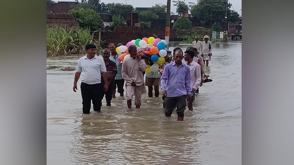 जलभराव से होकर गुजरते लोग।