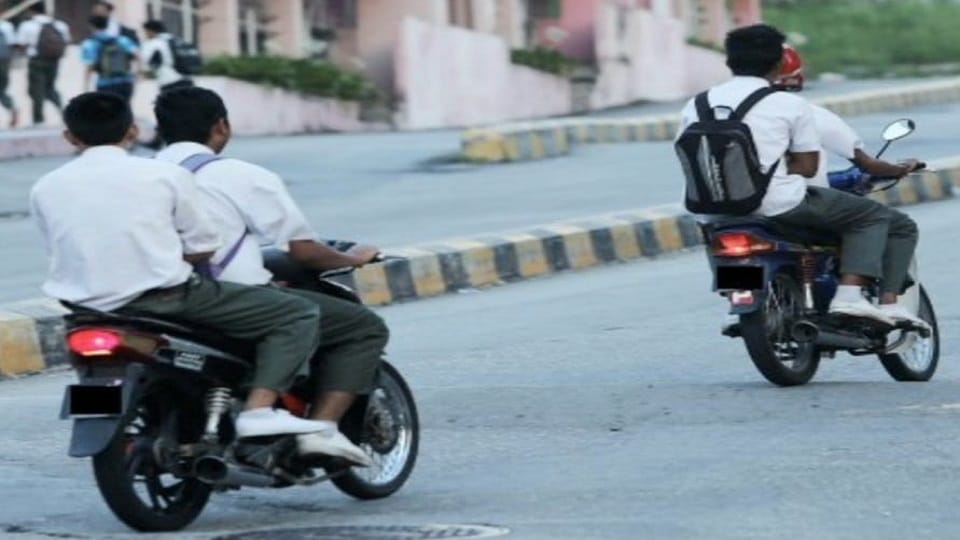 बाइक से स्कूल जाते स्कूली छात्र।
