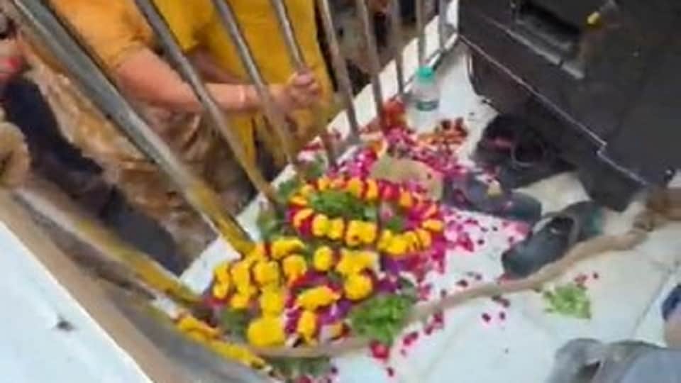 जूते-चप्पलों के बीच रखी फूल-माला और तुलसी