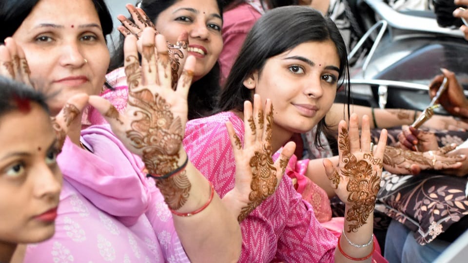 मेहंदी लगवाती सुहागिनें।
