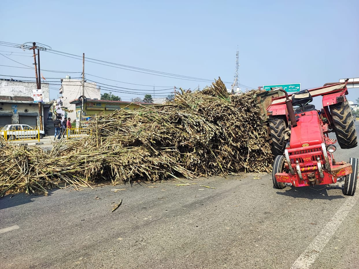 Tractor-trolley laden with sugarcane overturned on the highway, traffic blocked