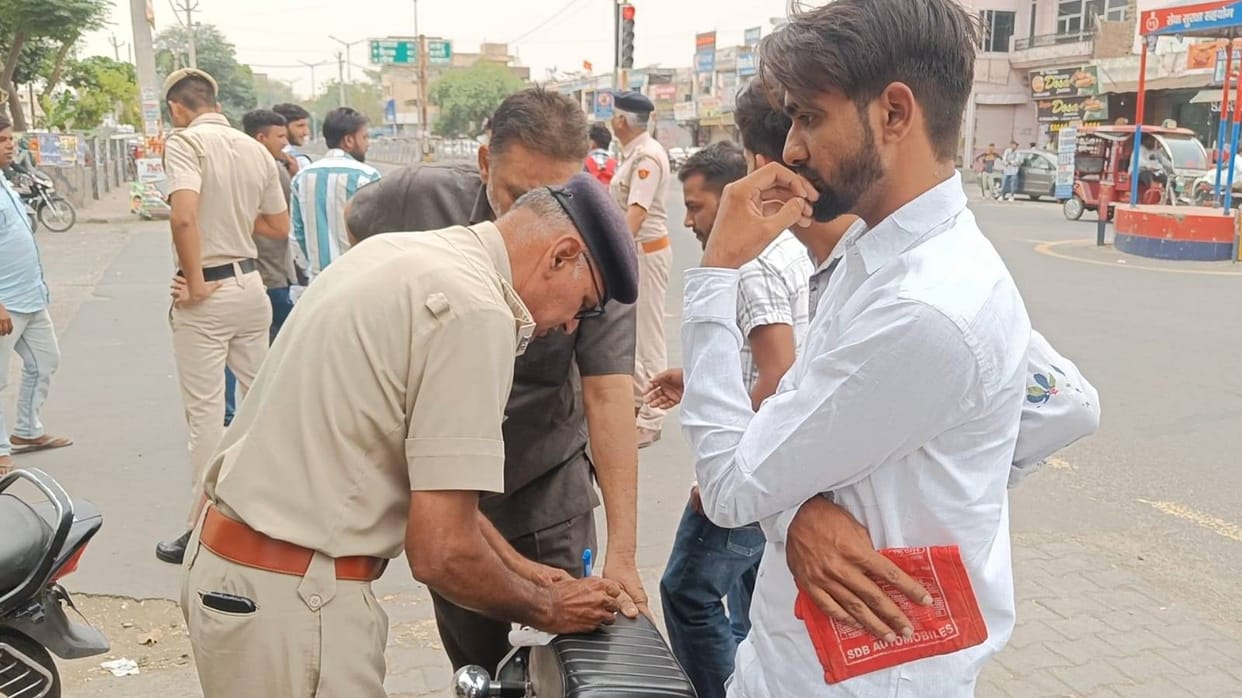 Policemen cutting challans of motorists at Lalbatti Chowk in Fatehabad.