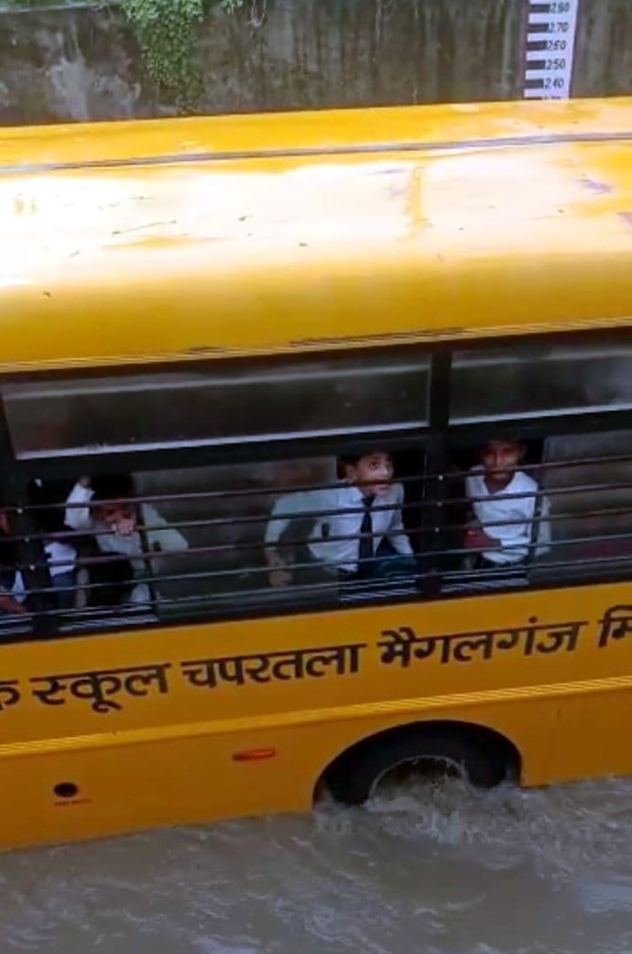 school bus stuck in water under railway underpass