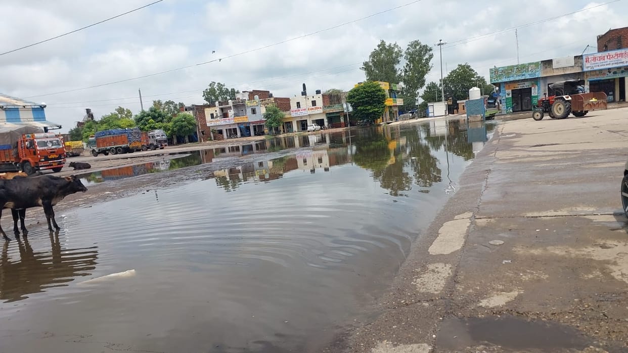 The agent is troubled by the rain water accumulated at the gate of the grain market