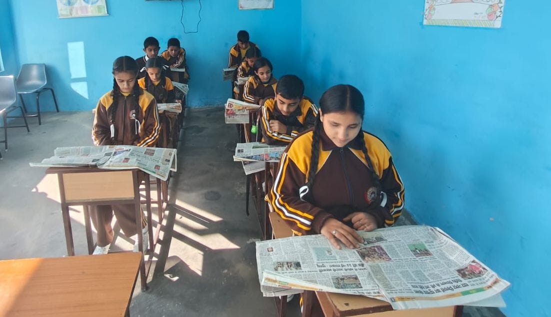 School students reading newspaper before syllabus