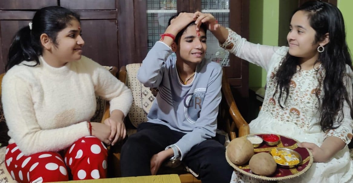 Sisters wish good luck to their brothers by applying tilak on their forehead.