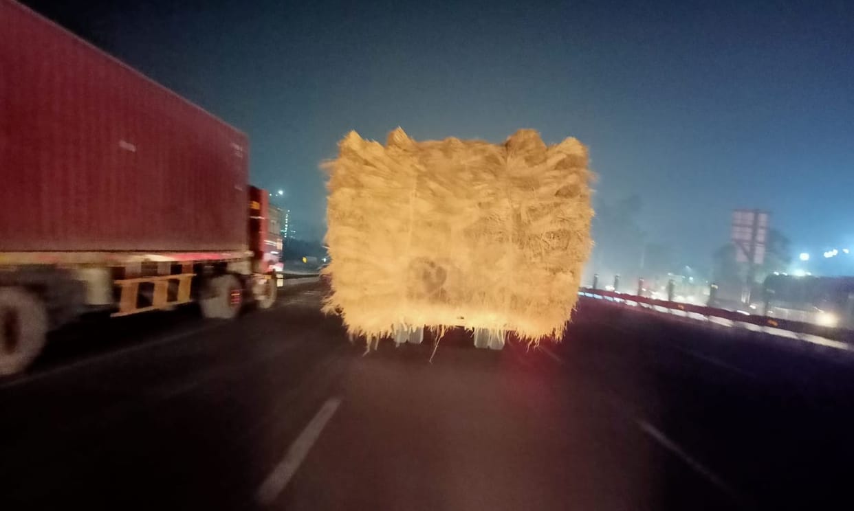 Tractor-trolley full of stubble running on the highway without reflector