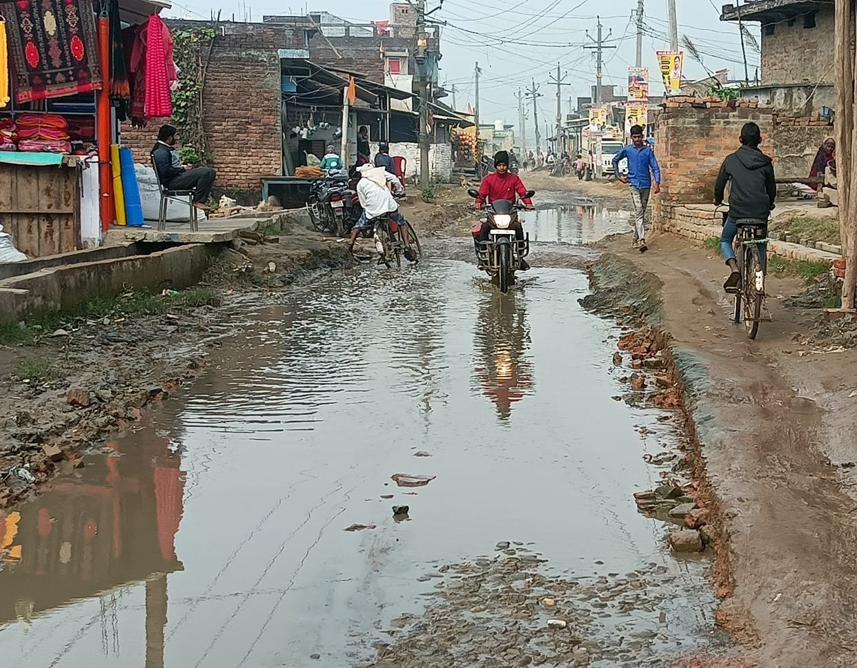 People forced to travel through muddy potholed road