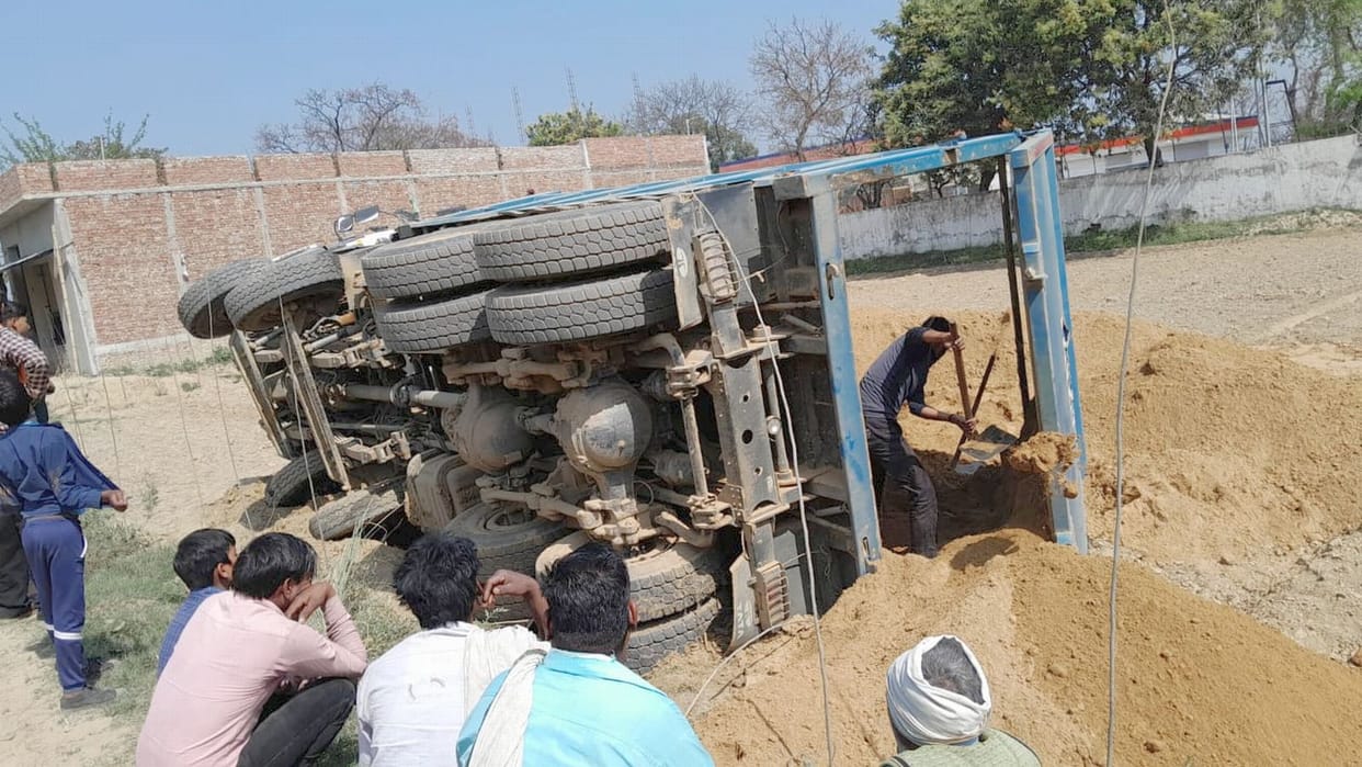 Dumper carrying soil overturns, driver trapped in cabin