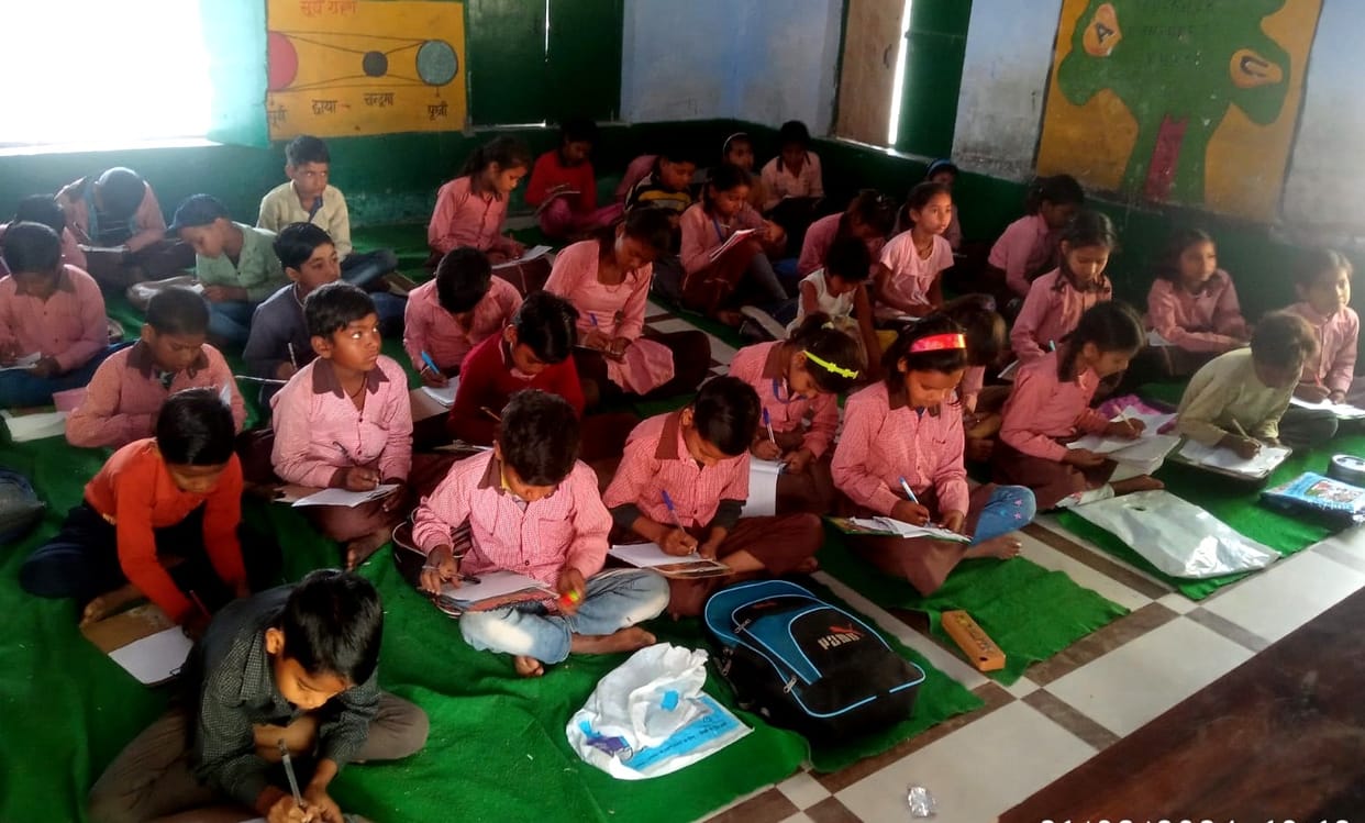 Youngsters are giving exams sitting on school mats.
