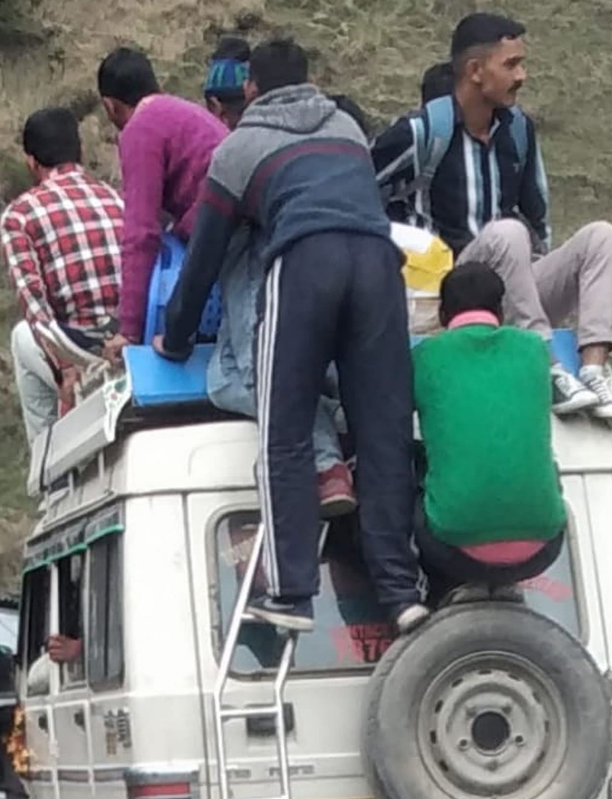 Crowded passengers, people sitting on the roof, even hanging from the stepney