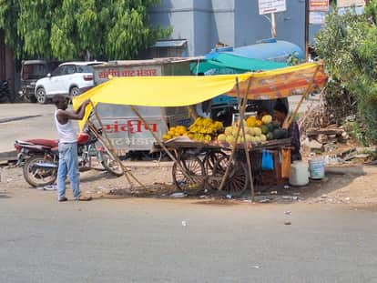 धूप से बचाने फल को ढकता दुकानदार