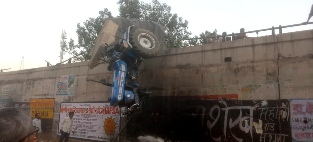 Tractor-trolley hanging on overbridge due to collision with bus