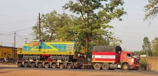 A crowd of people started looking at the engine of the goods train riding on a 42 wheeler truck.
