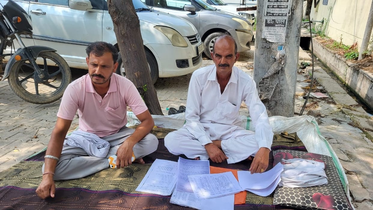 Father and son sit on dharna outside BDPO office