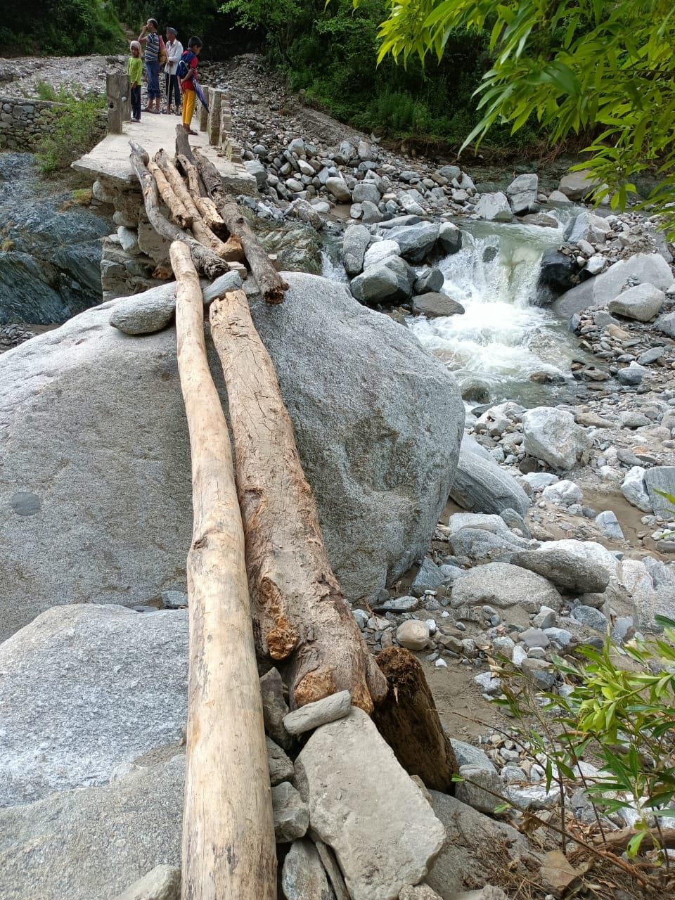 Villagers are crossing the river with the help of wooden poles