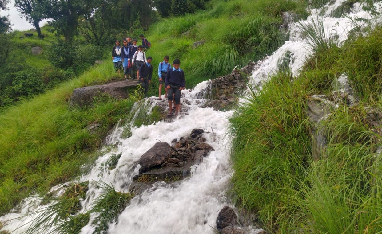 Students risking their lives to reach school by crossing the swollen drain.