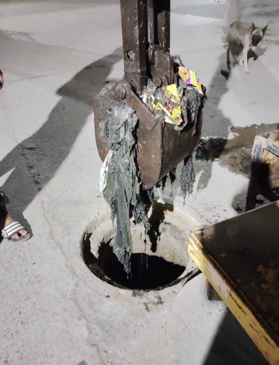 Cleaning of manhole started with grave machine, polythene and cow dung coming out from sewer.
