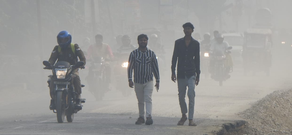 People commuting amidst the flying dust on Ashok Marg of the city.