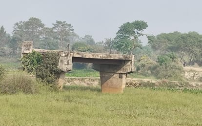 People cross the broken bridge carrying their bicycles on their shoulders