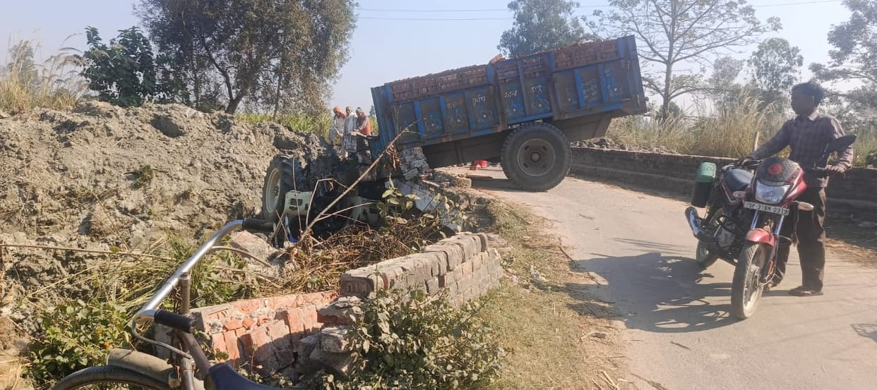 Tractor-trolley hanging after breaking the railing of the culvert