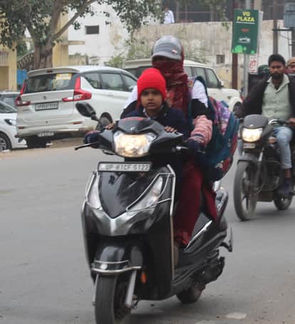 सर्दी में स्कूटी पर स्कूल से बच्चों को घर ले जाती महिला