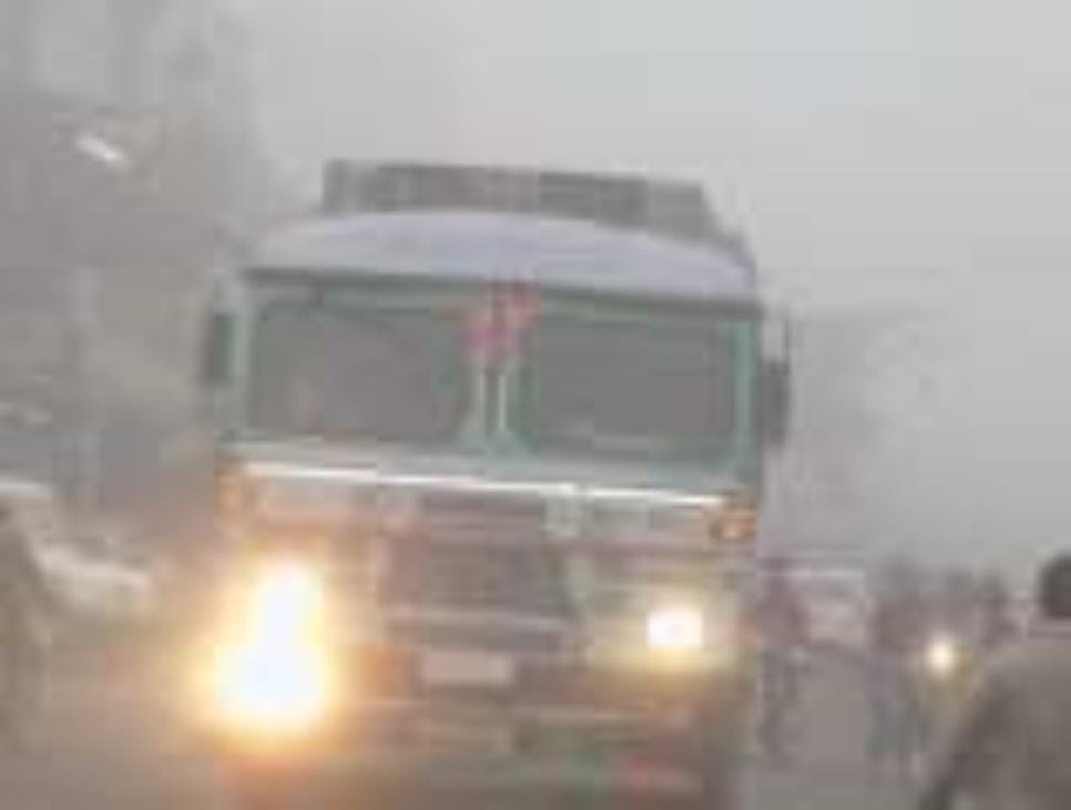 Vehicles passing with headlights on in dense fog