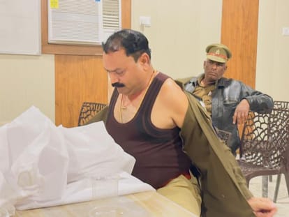 थाना जलेसर में फर्जी आईपीएस अधिकारी से वर्दी उतरवाते पुलिस कर्मी। 