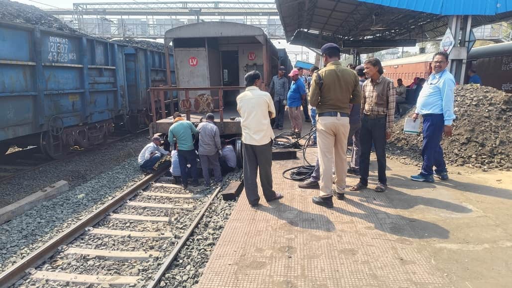 दुर्घटनाग्रस्त मालगाड़ी और सुधार कार्य करते रेलवे अधिकारी