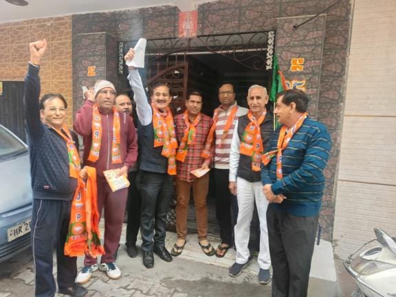 Corporation's assistant project officer is busy campaigning for his wife with a BJP scarf around his neck.