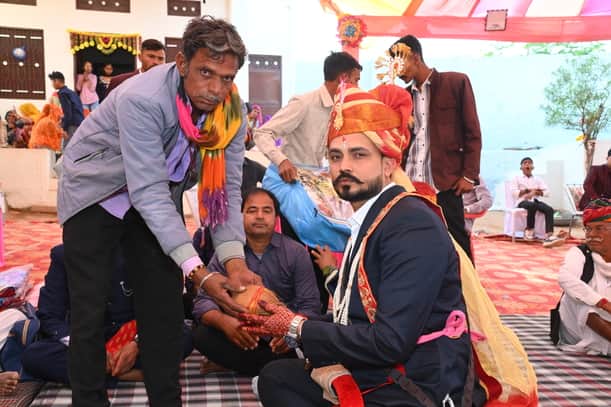 दूल्हा रुपए और नारियल लेता हुआ