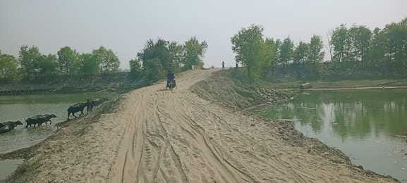 Work is being carried out by putting soil on the road cut by flood